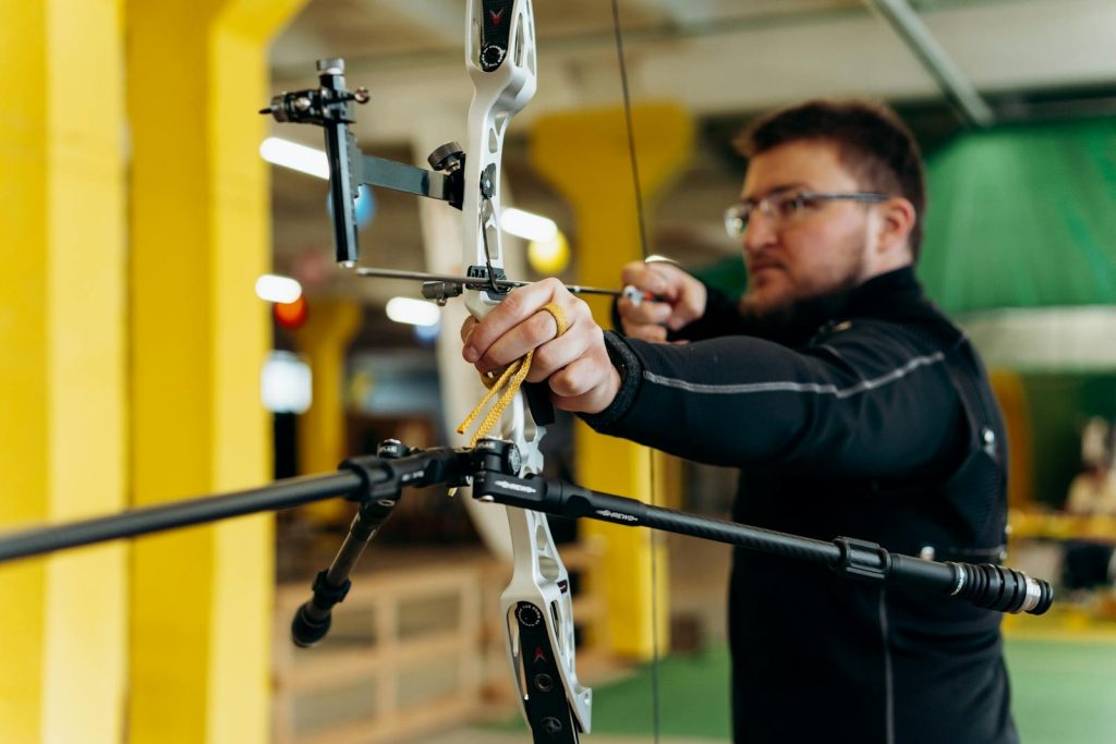 Man concentrating on aiming during an indoor archery practice session.